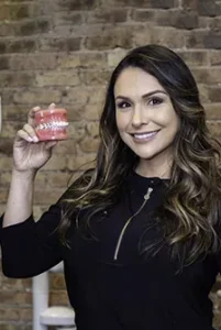 Sonrisa Family Dental team member holding dental model against brick wall