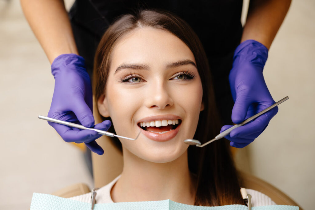 Happy patient during a visit to the dentist. The doctor is checking teeth using a dental instrument, ensuring proper oral care in the dentistry clinic.