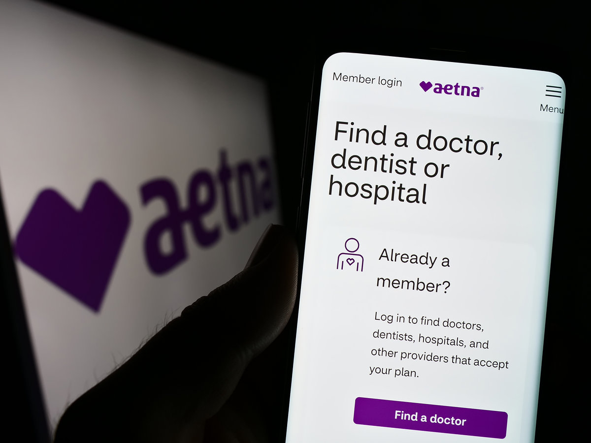 Stuttgart, Germany - 01-14-2023: Person holding cellphone with webpage of US managed healthcare company Aetna Inc. on screen in front of logo. Focus on center of phone display.