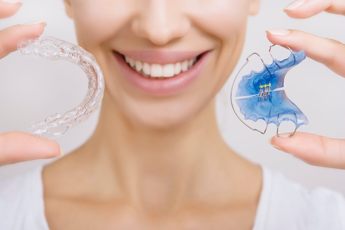 Beautiful Smiling girl Holding Retainer for Teeth (Dental Braces) and Individual Tooth Tray. Orthodontics Dental Theme, Methods of Teeth (Bite) Correction, Close-up