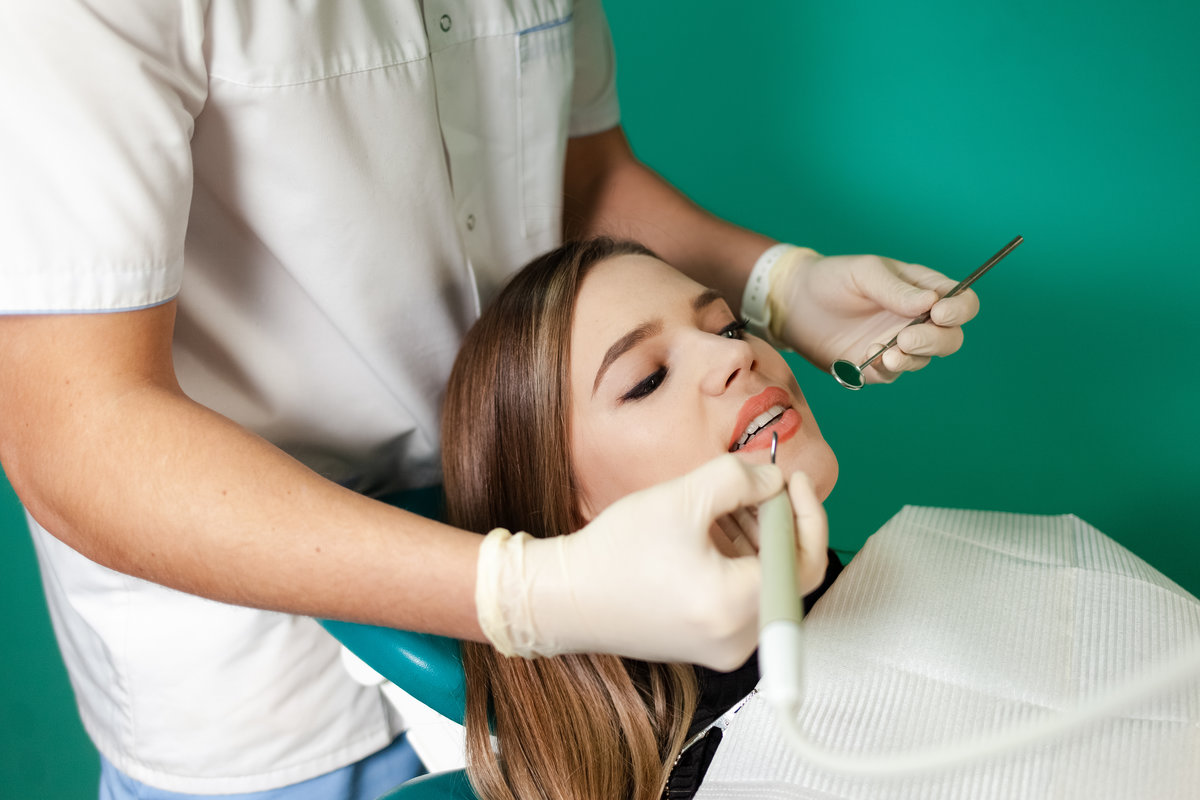 Dentist removes tartar from his patient’s teeth