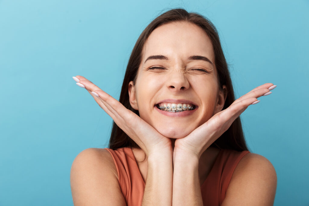 Close up of a cute lovely young girl standing isolated over blue background, grimacing