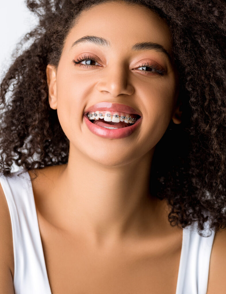 laughing african american girl with dental braces, isolated on grey