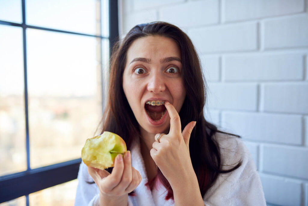 Girl with braces picks her finger in her teeth and eats an apple