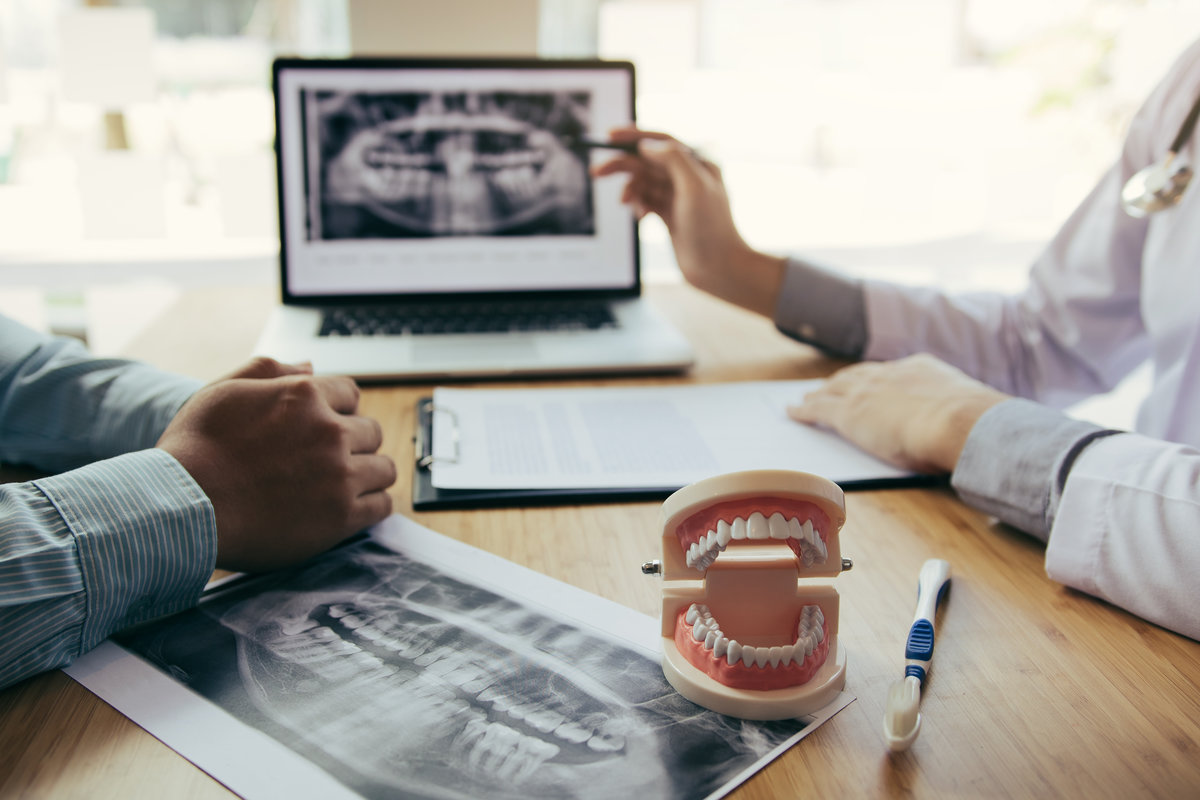 Dentists are discussing dental problems at report x-ray image on